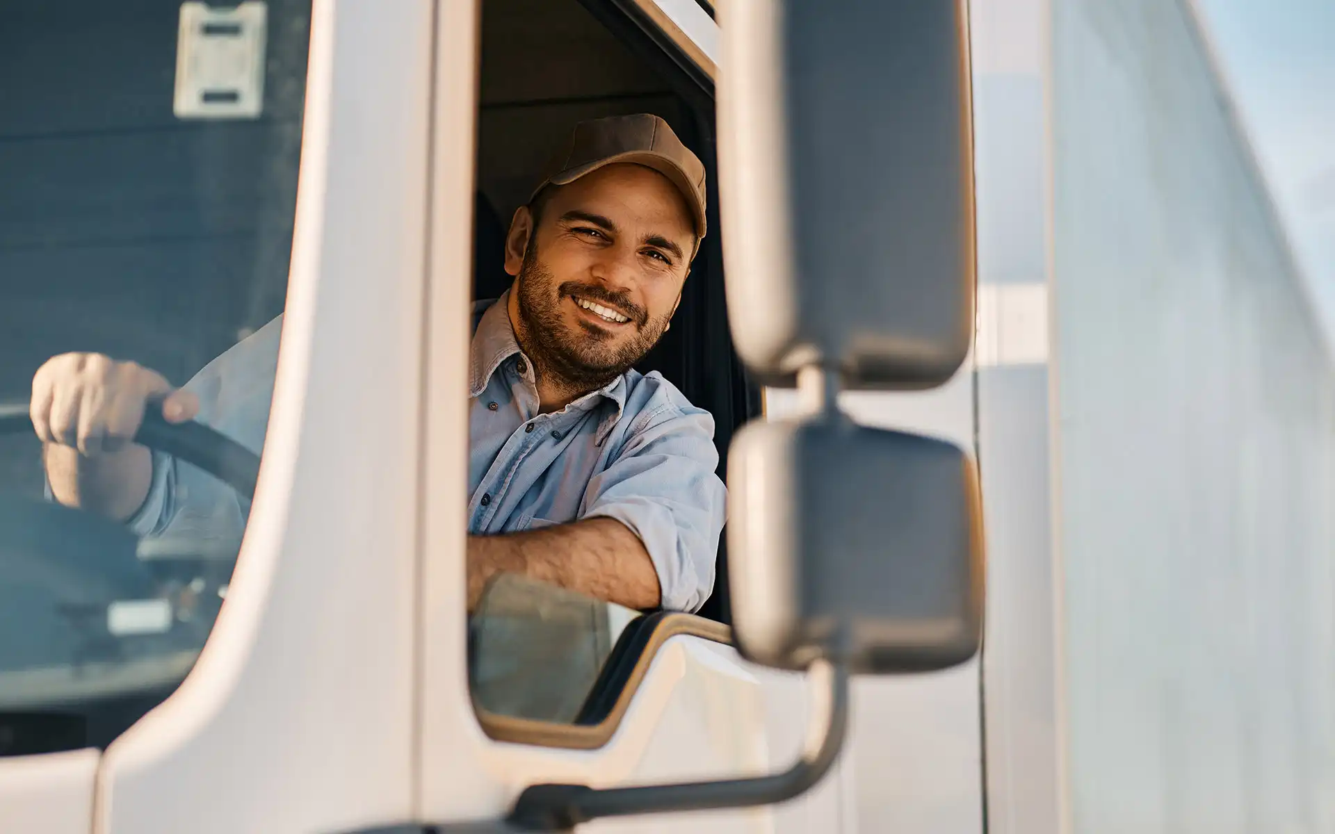 Transportfahrer schaut aus dem Führerhaus eines weißen Lkw