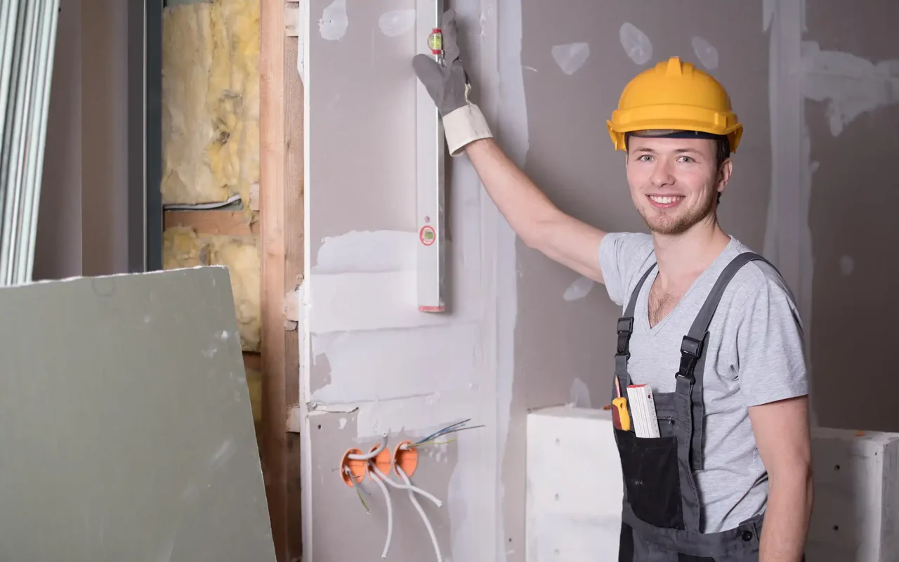 Handwerker mit Schutzhelm bei Arbeiten an einer Wand